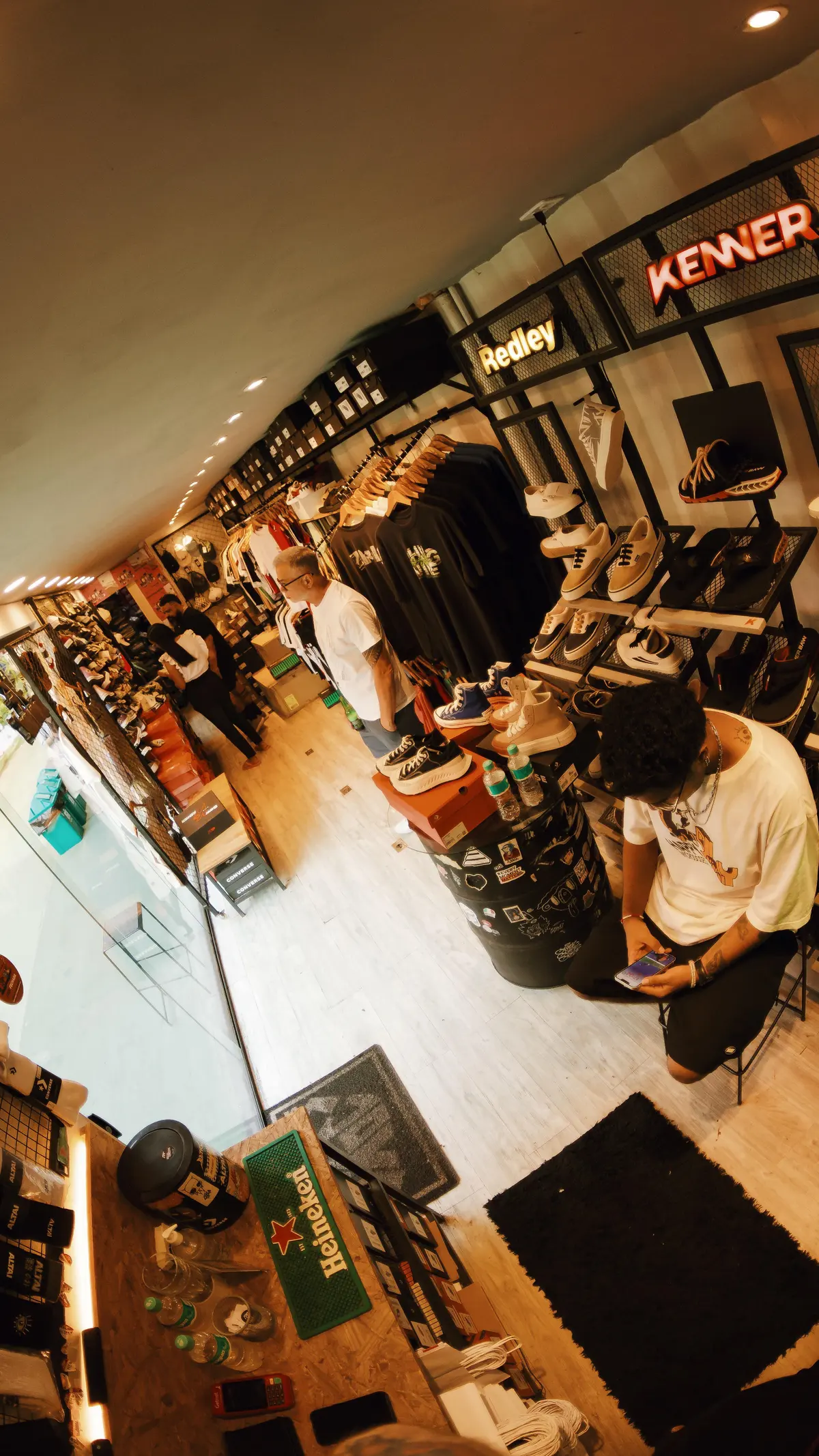A Joy por dentro, vista do alto: a parede de tênis, as araras e clientes escolhendo